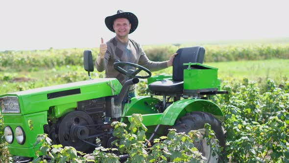 Attractive Young Farmer Standing By a Tractor