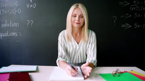 Webcam View of Teacher Having Online Maths Lesson Sitting at Chalkboard