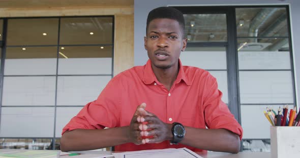 African american creative businessman at desk in office talking during video call