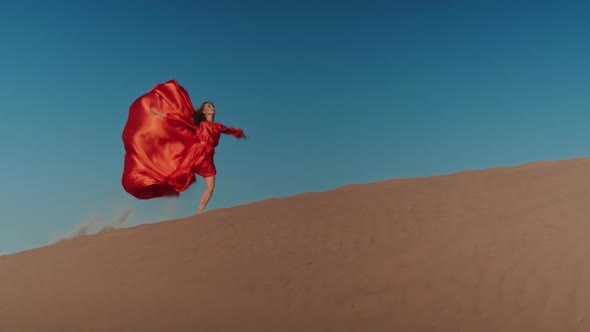 An Asian Woman in a Red Dress Dancing on Sand Dunes