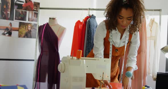 Front view of African American female fashion designer looking at cloth samples in workshop 4k