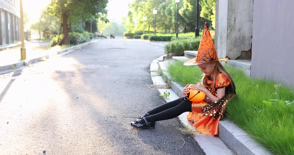 Cute little Caucasian girl in party costume with witch hat celebrating Halloween outdoor