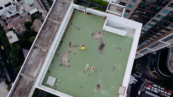 Drone Shot Of Models In Green And Yellow Dancing On City Rooftop