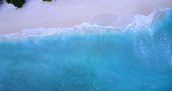 Daytime flying travel shot of a sunshine white sandy paradise beach and aqua blue ocean background 