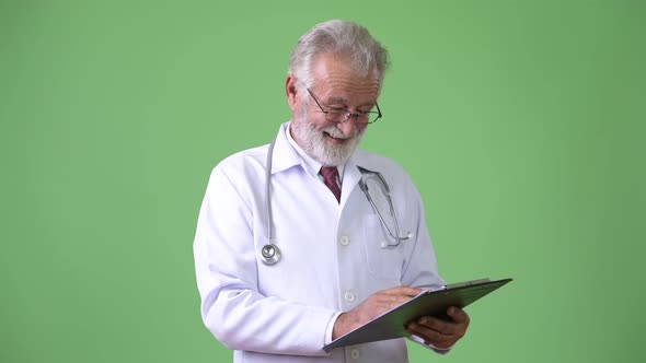 Handsome Senior Bearded Man Doctor Against Green Background