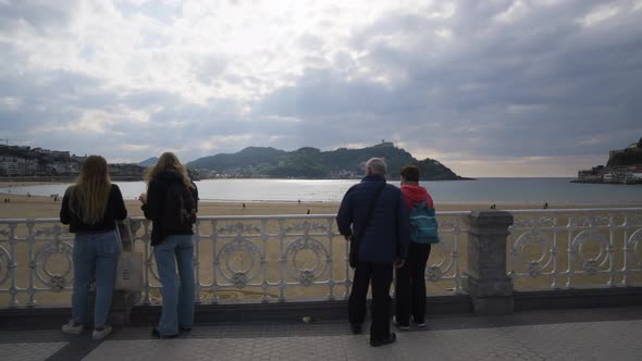 People admire majestic view of San Sebastian bay while on coastal pathway, gimbal motion