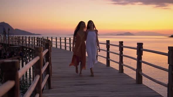 Two Female Friends in Summer Dresses are Having Rest on Tropical Beach While Walking Along the