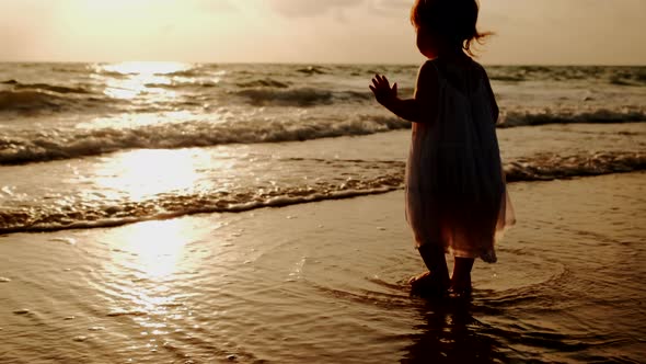 A Little Girl in a White Dress Stand Along the Beach