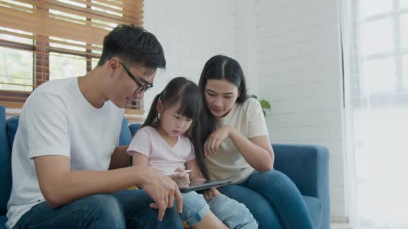 Happy asian family father mother and kid daughter sitting and using computer laptop technology