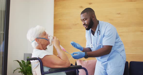 Video of african american male doctor keeping oxygen to caucasian senior woman