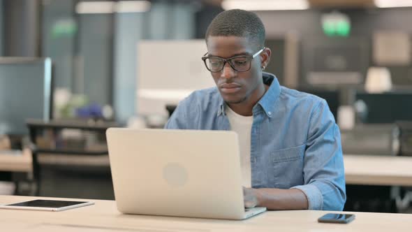Young African American Man Working on Laptop in Office