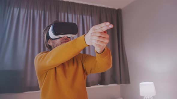 Young Man with VR Glasses Pretending To Shoot with His Hands