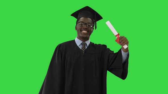 Happy African American Male Student in Graduation Robe Walking with Diploma and Talking To Camera on