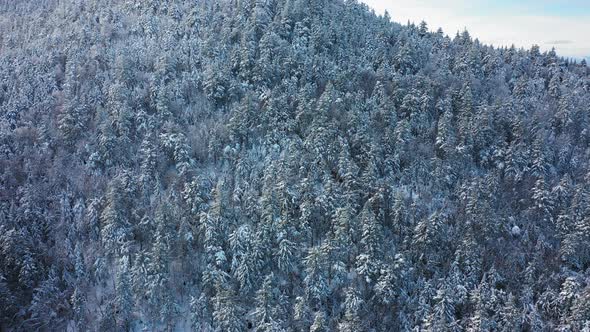 Aerial SLIDE to the right along the ridge of a snow covered mountain