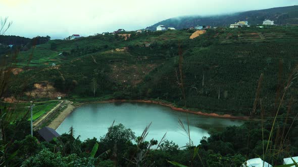 Static view of turquoise lake nestled in wooded hills near Da Lat. Vietnam. High angle