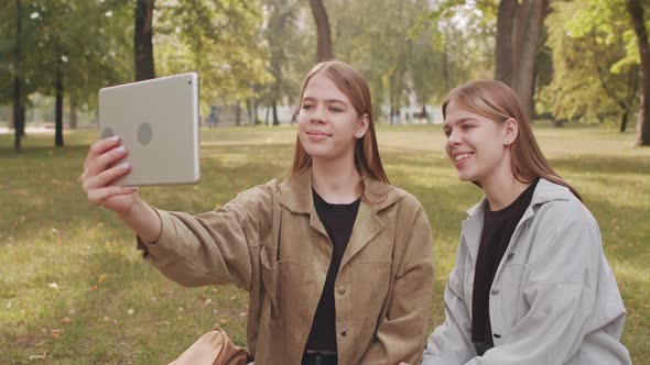 Happy Twin Sisters Chatting on Video Call in Park