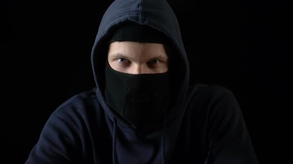 Hooded Serious Criminal in Balaclava Looking at Camera Piercing Glance