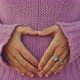 Woman hands do hearth sign on belly against violet sweater. Romantic and newborn life pregnant - VideoHive Item for Sale
