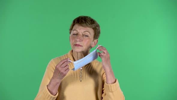 Portrait of Elderly Woman Is Texting on Her Phone Isolated Over Green Background.