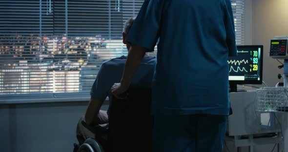 Nurse Pushing Wheelchaired Patient To a Window