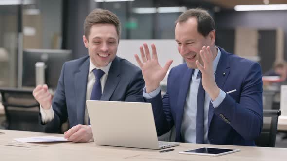 Businessman and Colleague Celebrating While Using Laptop