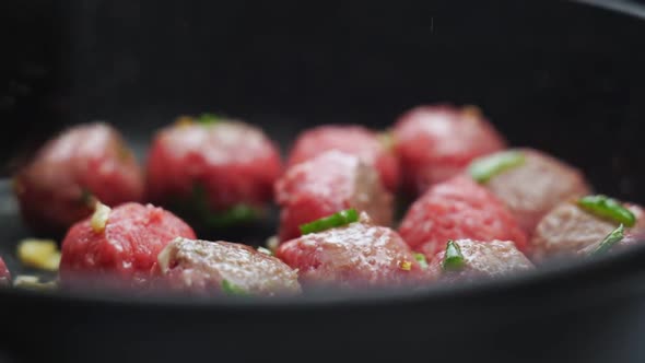 Unrecognizable person cooking meatballs on frying pan with oil