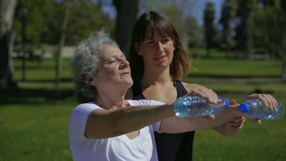 Calm Senior Woman Training with Cheerful Personal Coach in Park