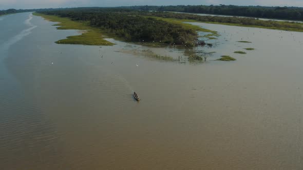 Aerial view of wooden boat with birds on Amazon River, Amazonia Peru 4K