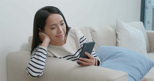 Woman look at mobile phone and sit on sofa