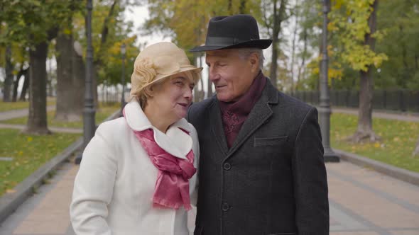 Mature Cucasian Couple in Elegant Clothes Standing in the Autumn Park and Talking