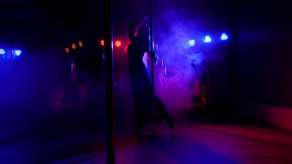 A Young Woman is Dancing on a Pole in a Dark with Bright Multicolored Spotlights