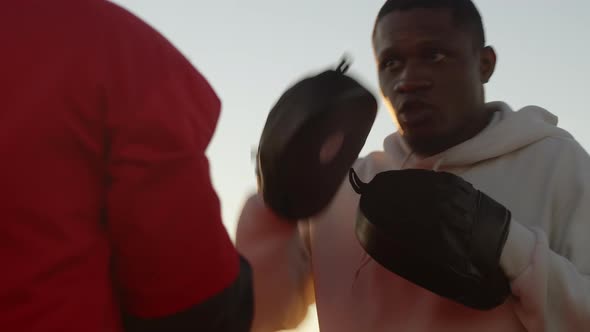 A Trainer with His Sportsman in Sportswear and Equipment are Engaged in Training Boxing Punches