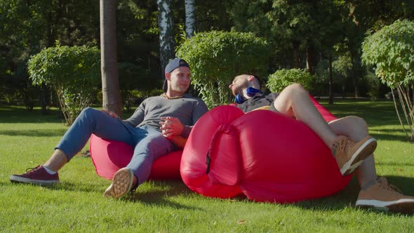 Same-sex Couple Relaxing on Bean Bags in Nature