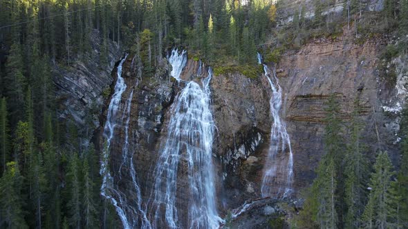 Drone flying backwards revealing a huge waterfall surrounded by woods in Canmore, Alberta. 4K footag