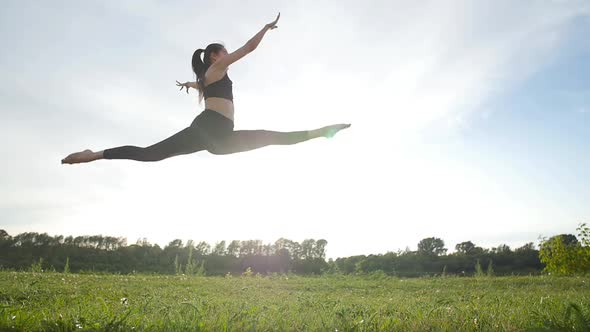 Sport and Healthy Lifestyle Concept. Young Athletic Woman in a Long Jump Sunny Sky Background