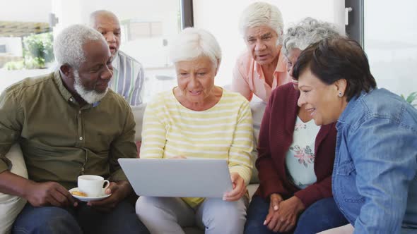 Happy senior diverse people talking and using laptop at retirement home