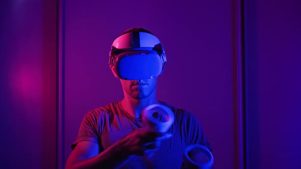 Young Man in VR Helmet Interacts with Virtual Reality Using Controllers