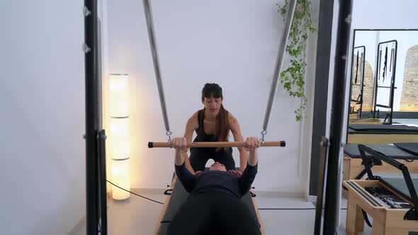 Woman doing exercises on pilates reformer with instructor