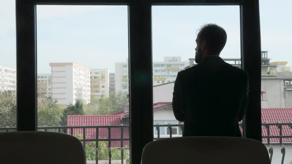 Silhouette of Businessman Sitting Next To a Big Window