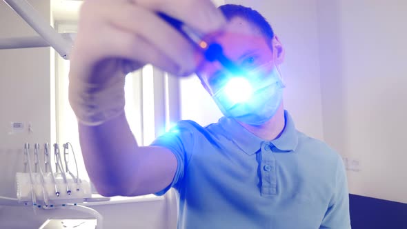 Portrait of Young Male Dentist Aiming and Pointing Flickering Flashlight Direct To Camera with
