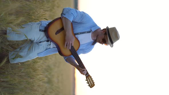 Vertical Video. Playing Acoustic Guitar Outdoors in Wheat Fields