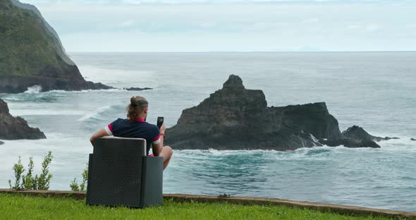 Man Uses Wireless Internet Connection in the Picturesque Seaside Area