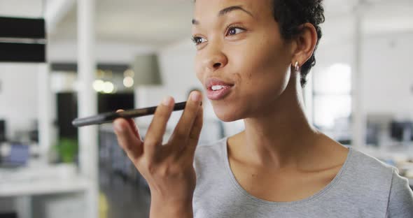 Portrait of happy biracial businesswoman making call in office