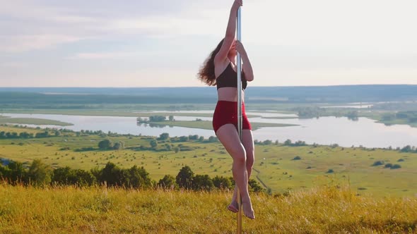 Pole Dance on Nature - Young Woman in Sports Clothes Crawling Up on Pole