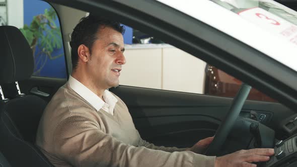 A Careful Man Is Studying the Steering Wheel of the Car and the Buttons Inside the Salon