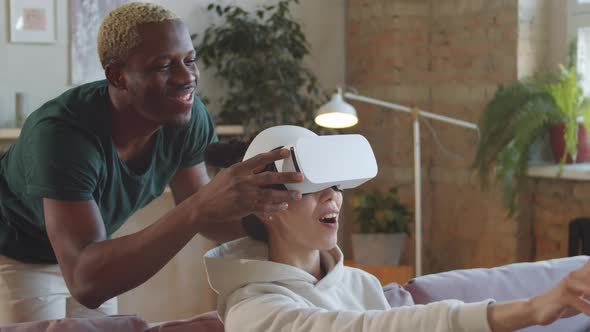 Excited Woman Using VR Headset with Assistance of Husband