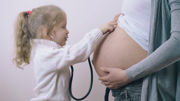 Funny Girl Puts Stethoscope on Pregnant Mommy Tummy in Room