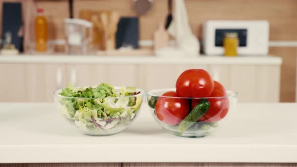 Tow Glass Bowls with Salad, Tomatoes and Cucumbers on the Kitchen Table