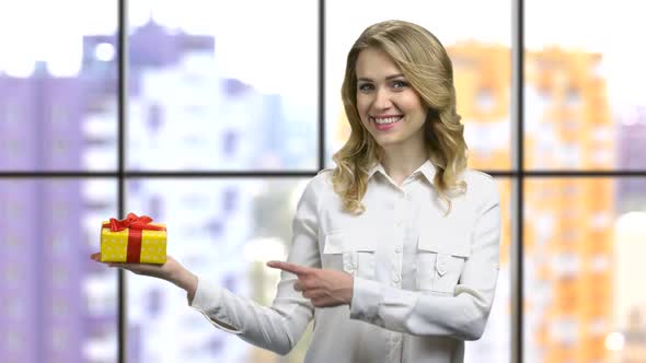 Young Girl in a White Shirt Pointing at the Gift Box