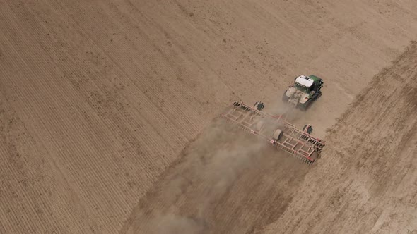 Aerial Top View of Tractor Cutting Furrows in Farm Field for Sowing Farm Tractor with Rotary Harrow